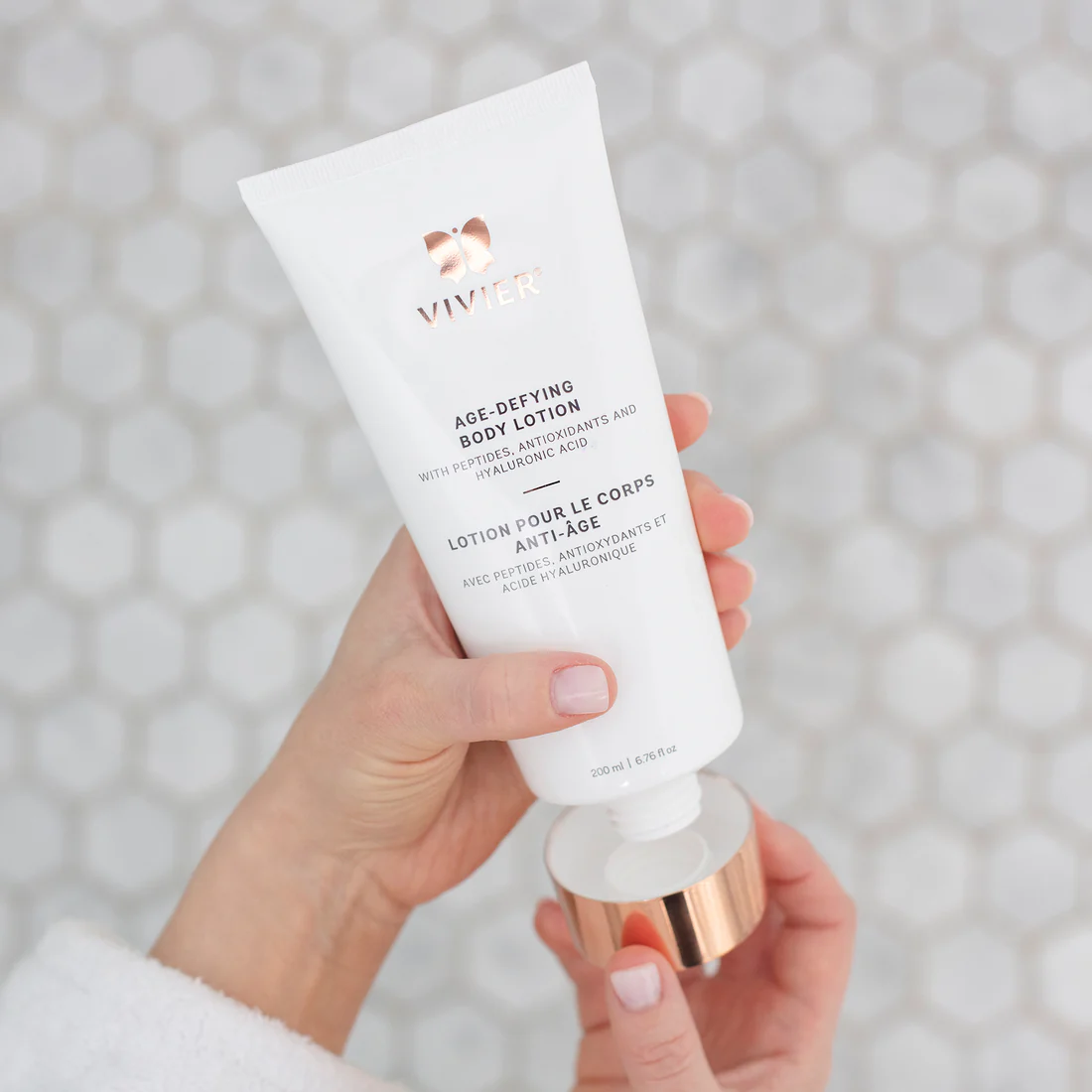 Hands opening a tube of Vivier Age-Defying Body Lotion