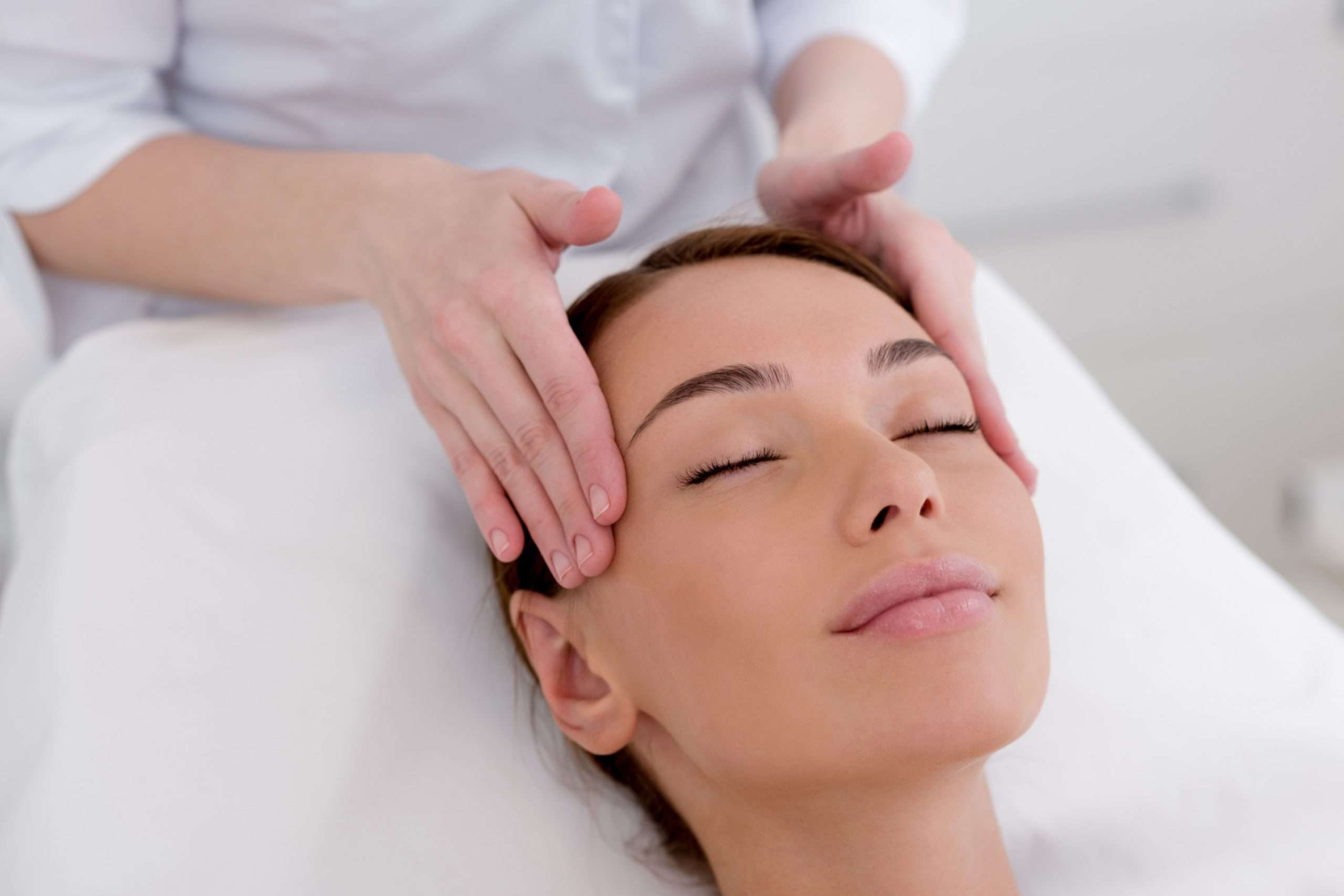 Hands massaging a person’s temples during a facial