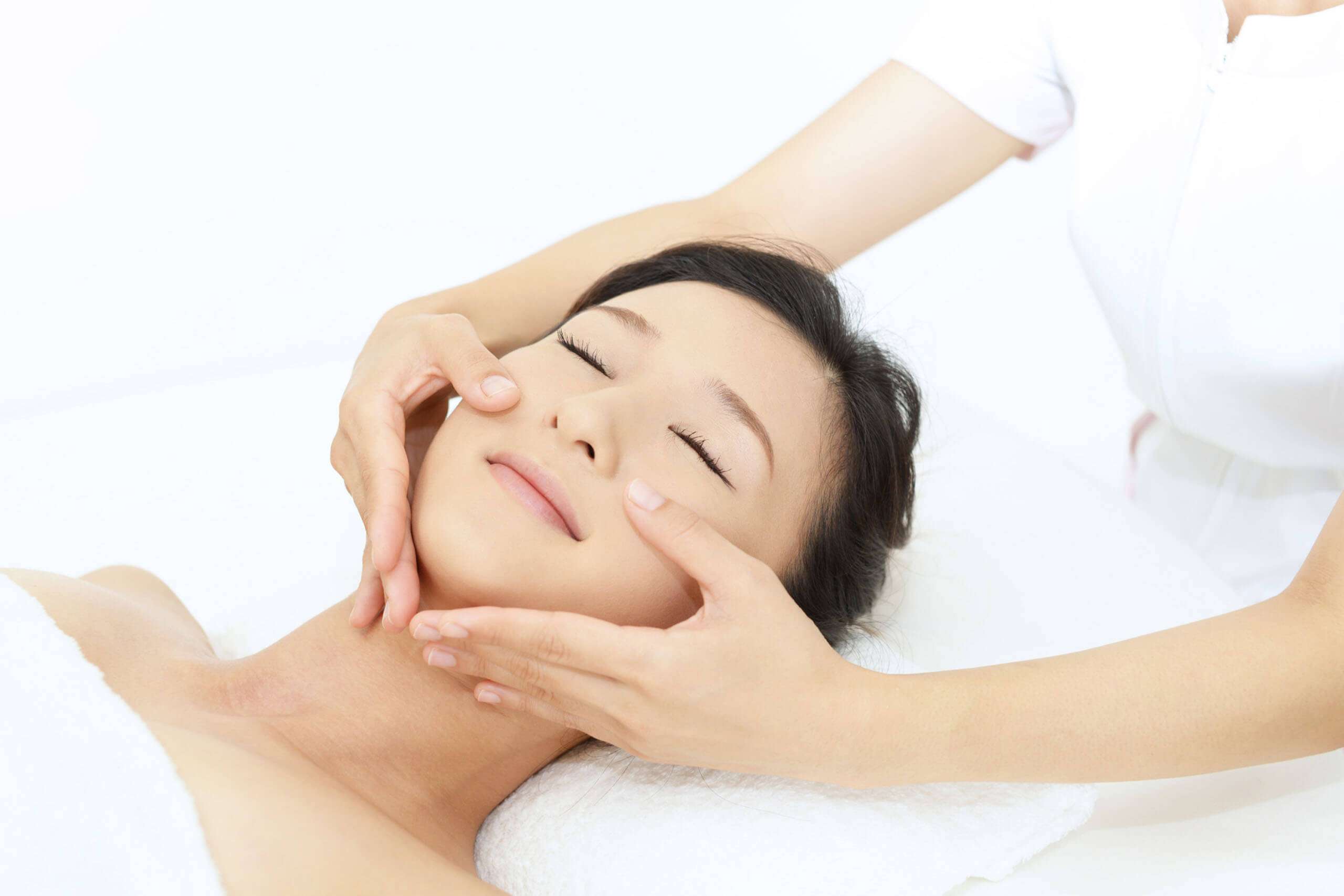 Hands massaging a person’s cheeks during a facial