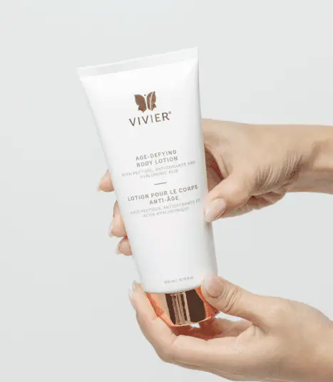 Hands holding a tube of Vivier Age-Defying Body Lotion