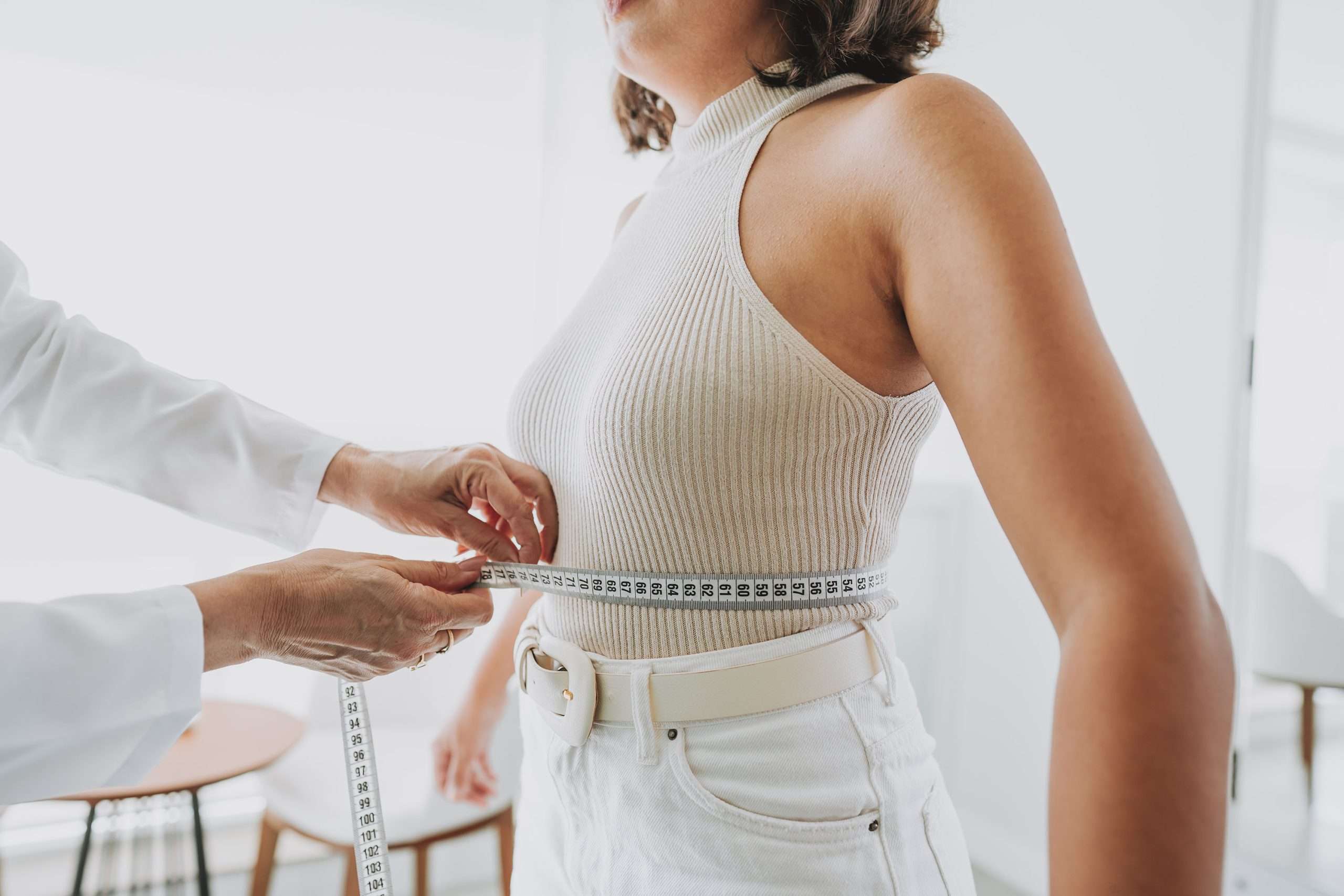 A measuring tape being wrapped around a woman’s waist